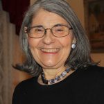 A woman in black with grey hair and glasses